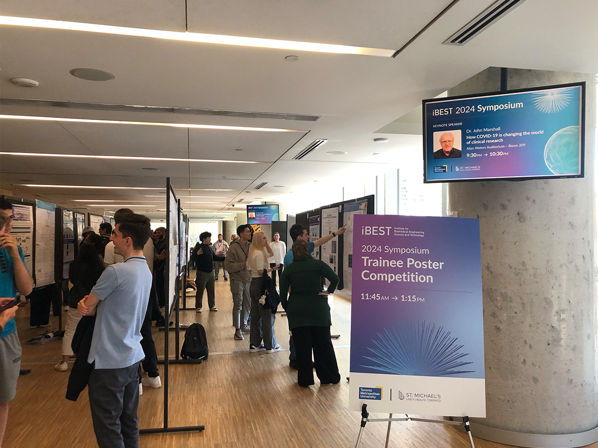 Several people examine posters set up in rows. 